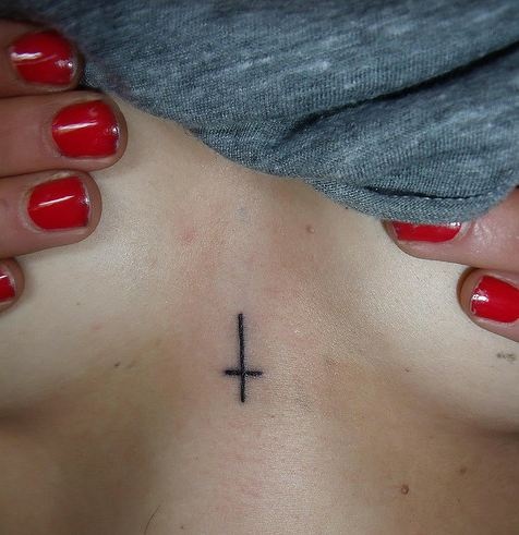 a woman's chest with a cross tattoo on it and red nail polishes