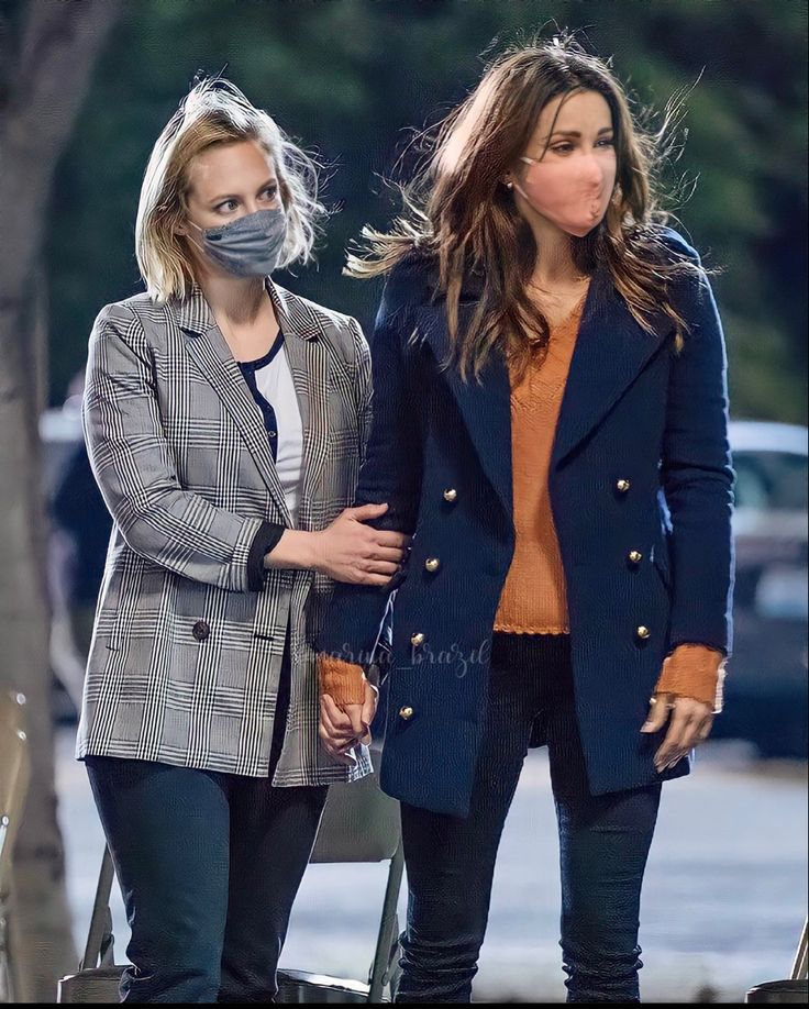 two women wearing masks walking down the street