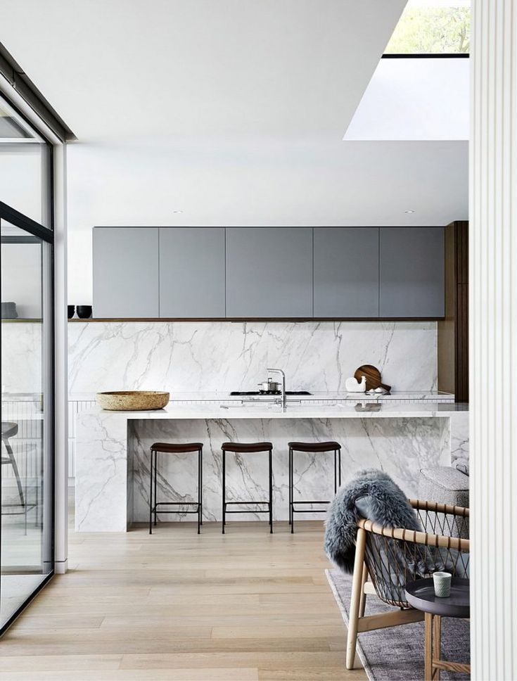 an open kitchen and dining area with marble counter tops, wooden flooring and stools