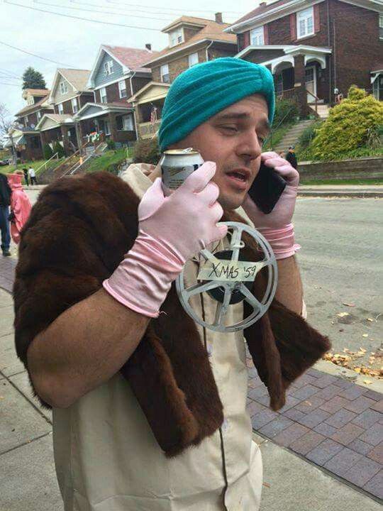 a man in a turban talking on a cell phone while wearing gloves and holding a peace sign