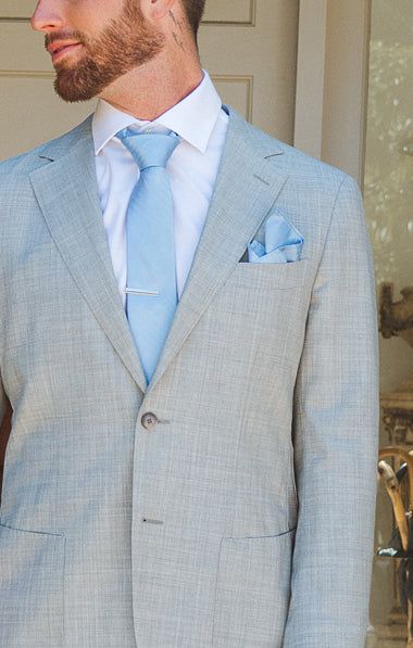 a man wearing a suit and tie standing in front of a door