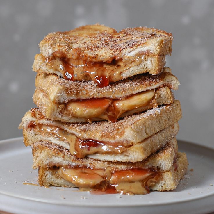 four pieces of french toast stacked on top of each other with caramel sauce and powdered sugar