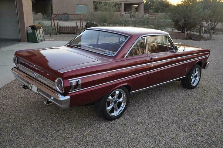 an old red car is parked in the driveway