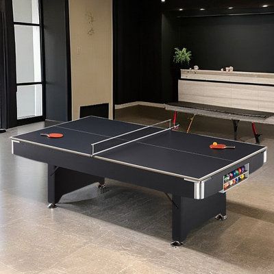 two ping pong tables in an empty room with black walls and white flooring