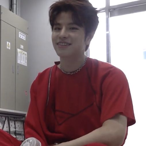 a young man in a red shirt sitting down