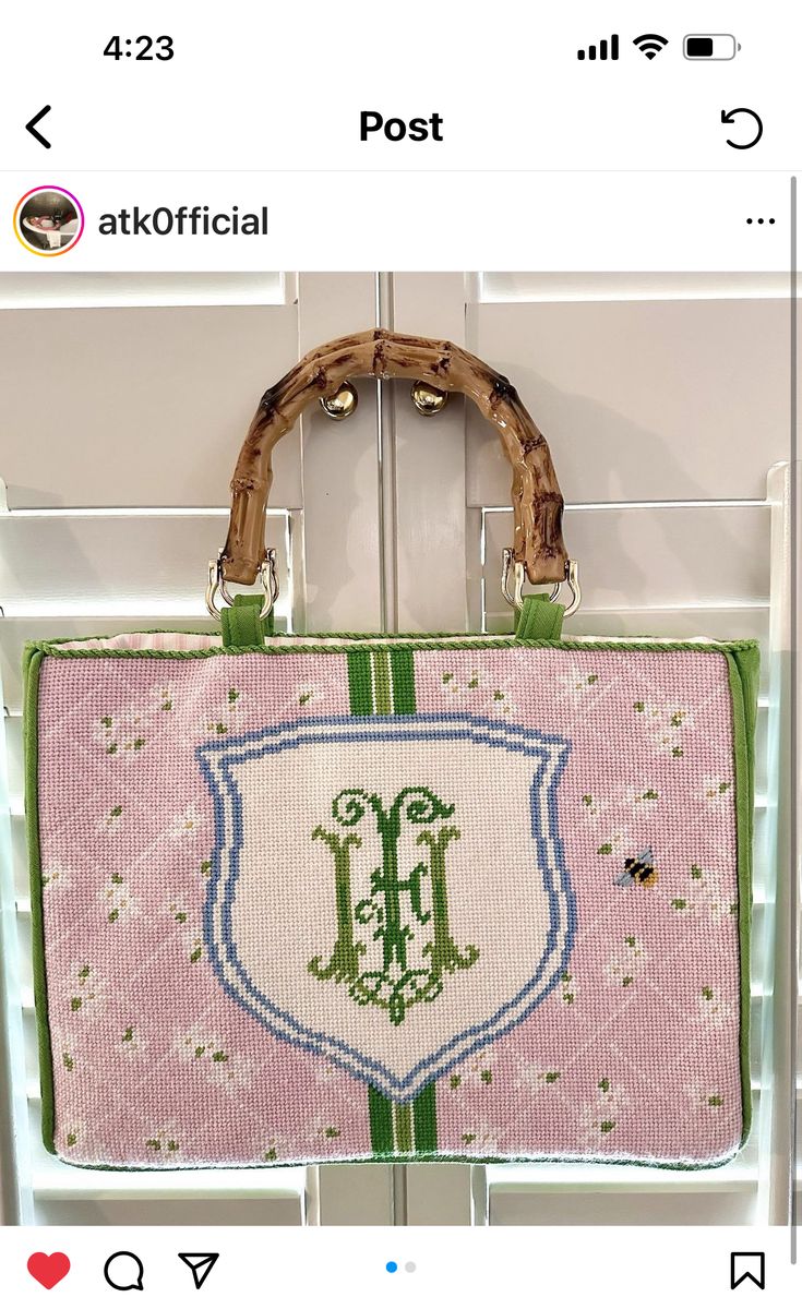 a pink and green purse hanging from a hook on a white door with the letter h in it