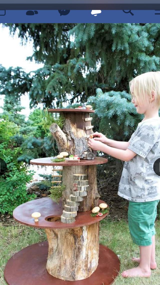 a little boy standing next to a tree stump with a bird house on top of it