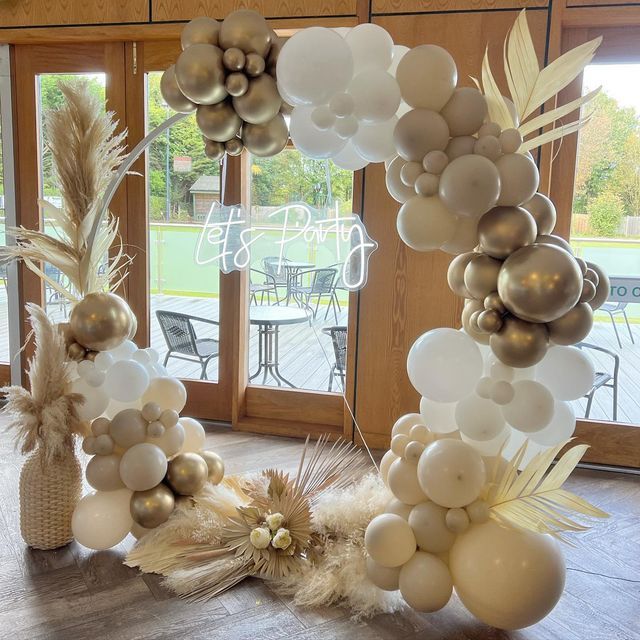 balloons and feathers are arranged on the floor in front of an open door with large windows