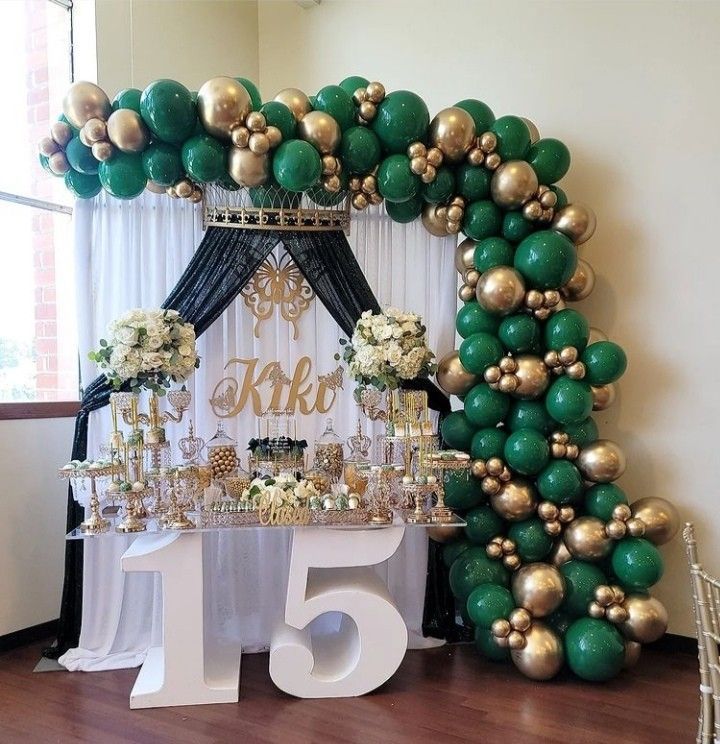 a table topped with lots of green and gold balloons