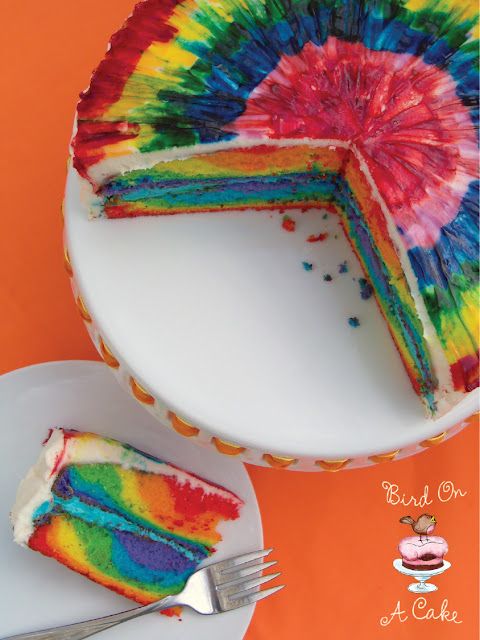 a tie dye cake on a plate with a slice cut out and ready to be eaten