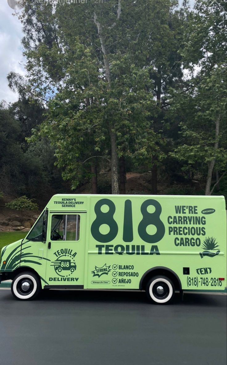 a green truck parked on the side of a road with trees in the back ground