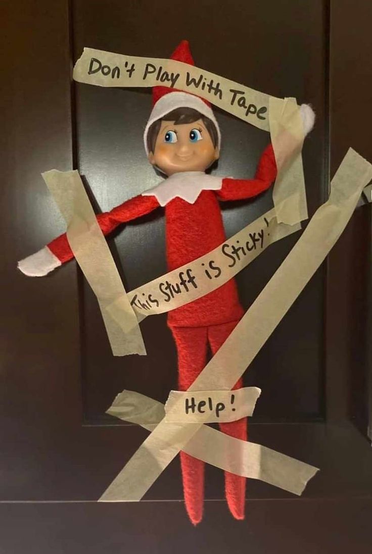 an elf with paper taped to it's face and holding up a sign that says, don't play with tape