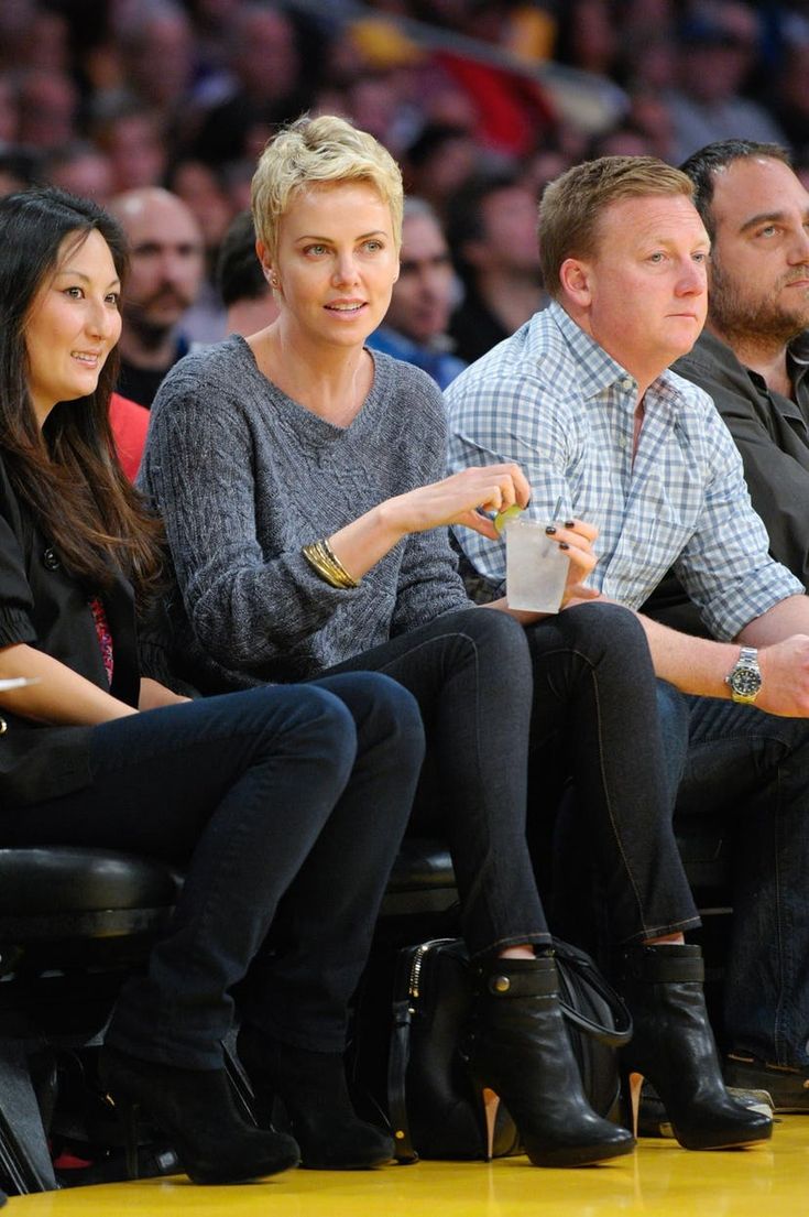 two women and a man sitting next to each other in front of a basketball court