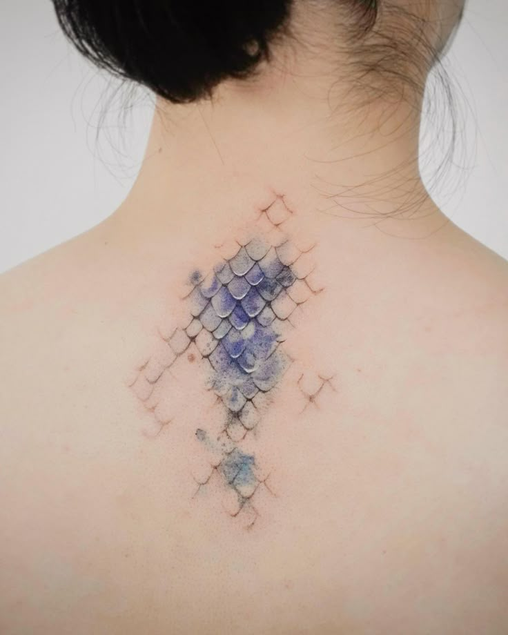 the back of a woman's neck with an abstract tattoo design on it