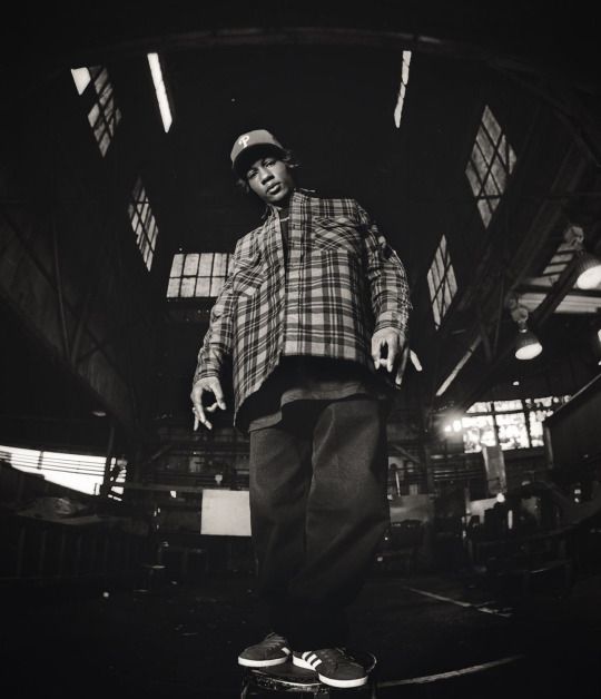 a black and white photo of a man on a skateboard in an indoor area