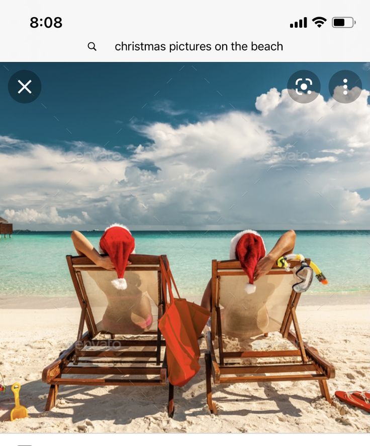 two people in santa hats sitting on beach chairs