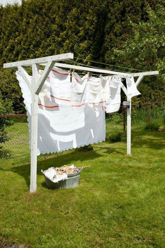 clothes hanging out to dry in the sun on a clothesline near a trash can