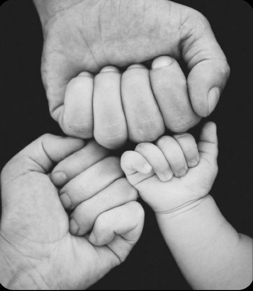 two hands holding a baby's hand in black and white