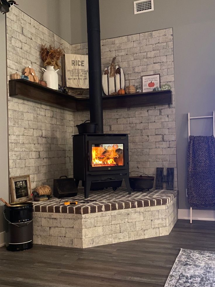 a wood burning stove sitting inside of a living room next to a wall mounted shelf