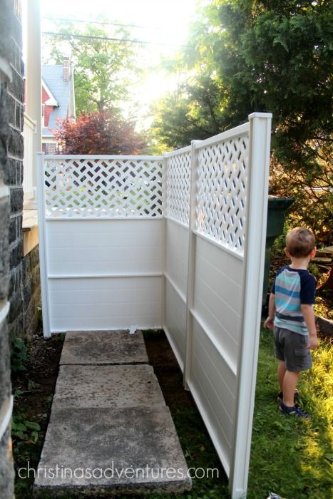 a little boy standing next to a white fence