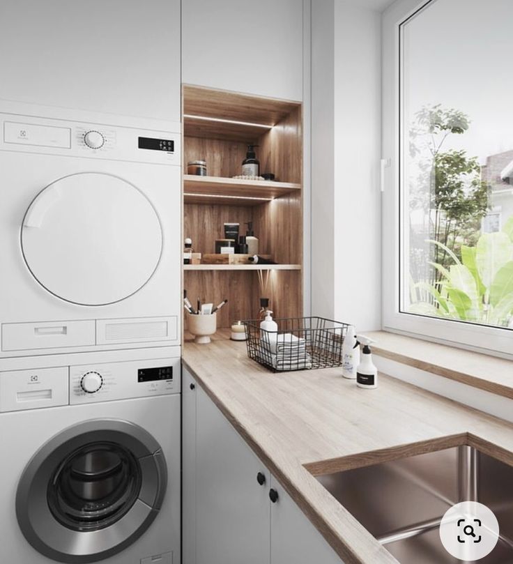 a washer sitting next to a window in a room with wooden counter tops and cabinets