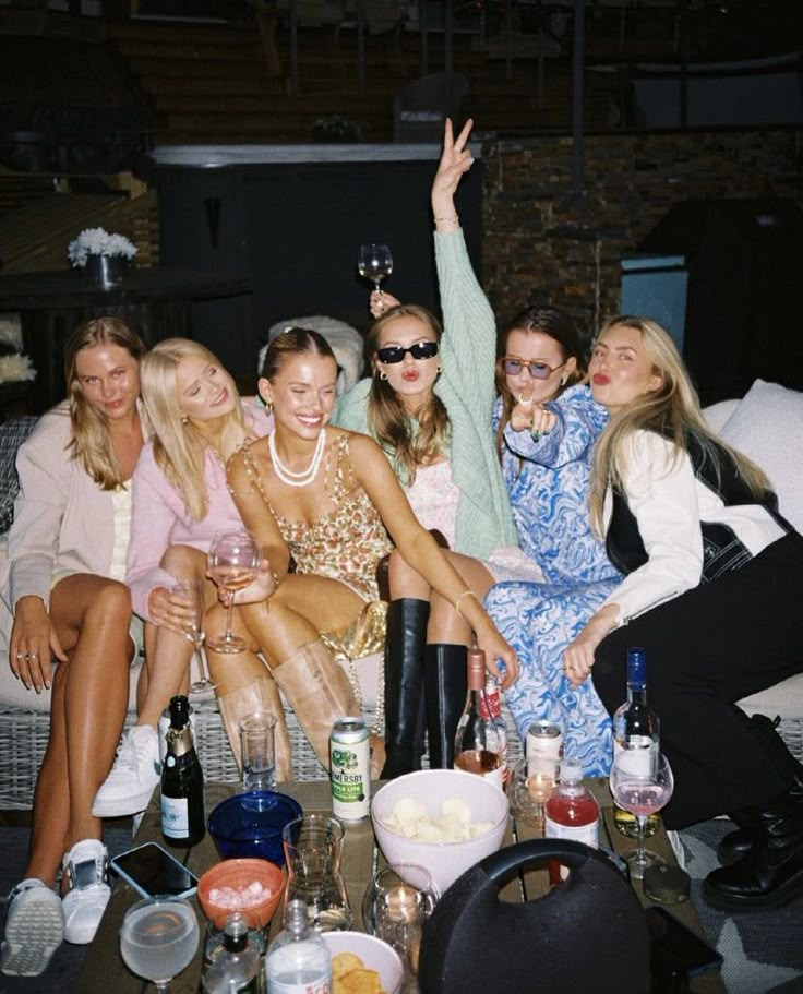 a group of women sitting on top of a couch next to each other holding wine glasses