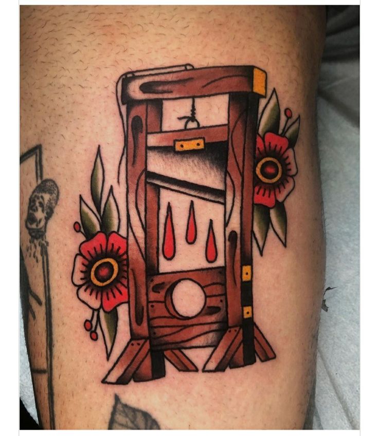 a tattoo with an old fashioned machine on it's thigh and flowers around the leg