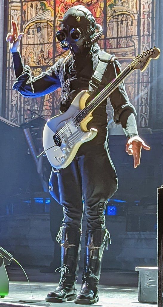 a man in black outfit playing guitar on stage