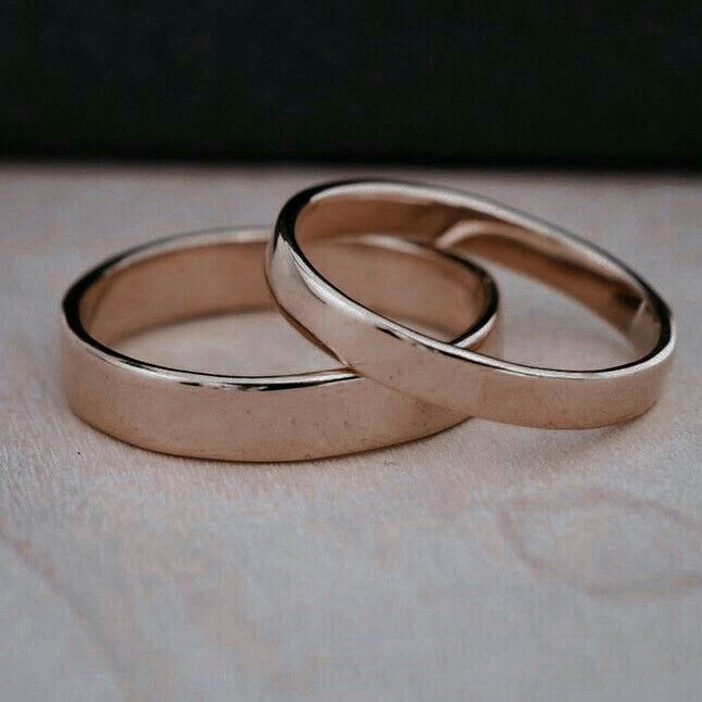 two wedding rings sitting on top of a wooden table