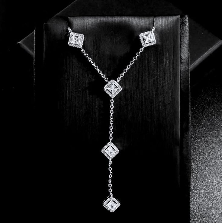 Modern and eye-catching, this lariat style necklace can complete the most sophisticated of bridal looks. All it takes is a simple glance at this delicate design to see its extremely subtle and classy look that makes a glamorous and feminine statement. Adorned with high grade cubic zirconia that capture the light in a dazzling array of sparkles, the necklace is rhodium plated for a smooth finish which enhances the intricate detailing and conveys a modern take on old elegance. Length of the necklace is 16" (approx. 40.6cm) with a 2" (approx. 5cm) extension chain for comfortable sizing. The lariat drop is 2.75" (approx. 7cm) in length. Closure is a secure lobster claw clasp. May be worn with both studs or long drop earrings, based on your preferences and style. Hypoallergenic - lead, nickel a Elegant Cubic Zirconia Backdrop Necklace With Delicate Chain, Diamond Lariat Drop Necklace For Wedding, Diamond Lariat Backdrop Necklace For Wedding, Diamond Lariat Necklace With Adjustable Chain For Wedding, Wedding Lariat Necklace With Adjustable Diamond Chain, Elegant Silver Backdrop Necklace With Delicate Chain, Luxury Silver Lariat Necklace For Wedding, Elegant Drop Necklace With Delicate Chain For Formal Occasions, Classic Formal Lariat Necklace With Clavicle Chain