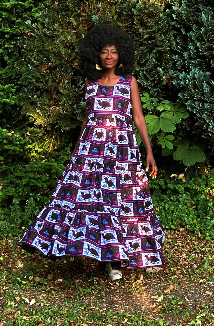 "A gorgeous tiered dress in a contemporary African print in a purple and white with dashes of deep green, blue and fuschia. The dress is tiered and full giving a swish which enhances the way the dress falls on the wearer. Wear with or without a belt. Closure is by a back zip with side pockets. A dress that will take you through the changing seasons. On warmer days wear with sandals or trainers and in cooler weather wear your boots, layer with a skinny long top and throw on your leather jacket or coat.  Partial lining at the upper part of the dress. 100% Cotton. Handmade in Ghana.  length of the dress is 56\"-57\"  Although we do our best to make sure that the colours displayed on our Website are accurate, the actual colours may vary. Differences in monitors and the device you use to view t Weather Wear, Bird Print, Purple And White, Changing Seasons, Tiered Dress, Deep Green, Fall Dresses, African Print, Maxi Dresses