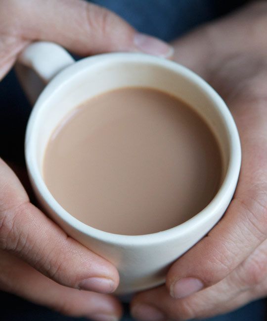 two hands holding a white cup of coffee