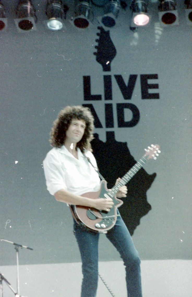 a man standing on top of a stage holding a guitar