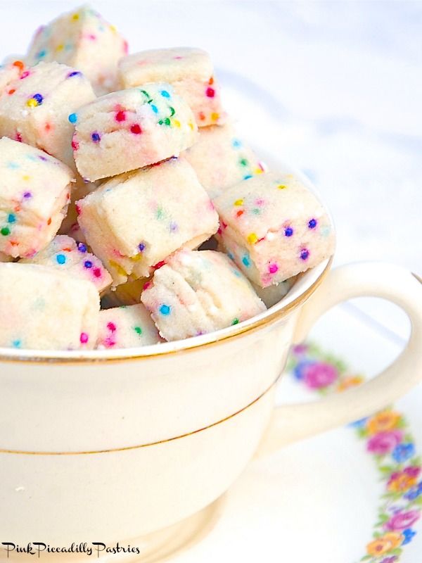 a white cup filled with sprinkles and marshmallows on top of a table