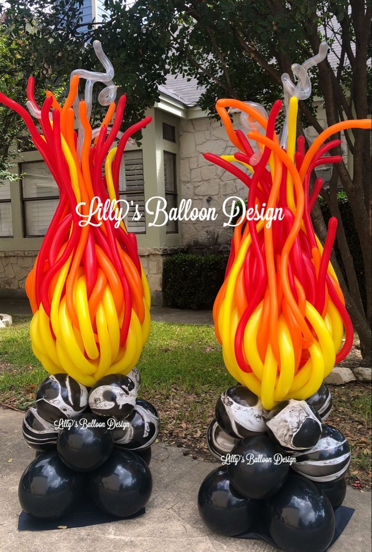 two blown glass vases sitting on top of black balls in front of a house