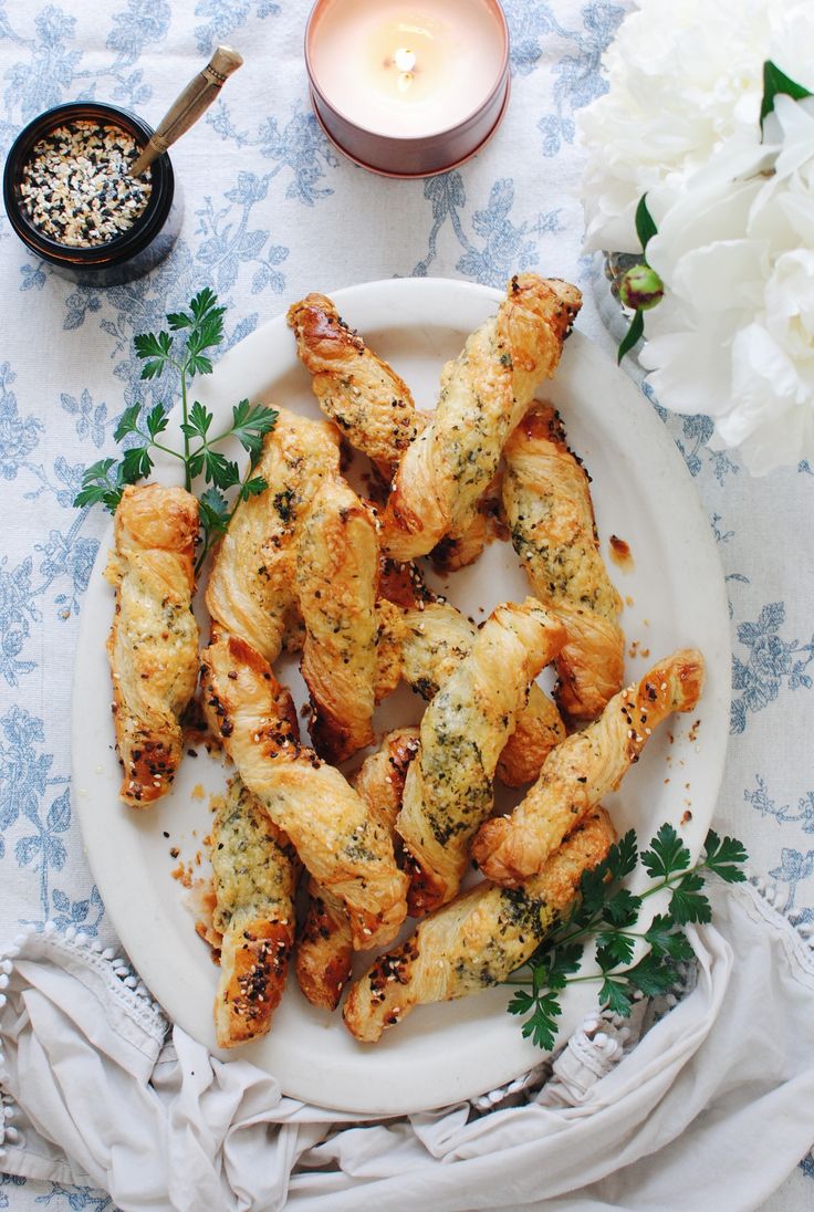 a white plate topped with chicken wings and garnished with herbs next to a candle