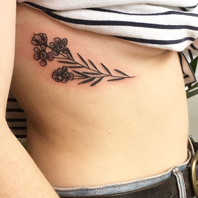 a close up of a woman's stomach with flowers on her left side ribcage