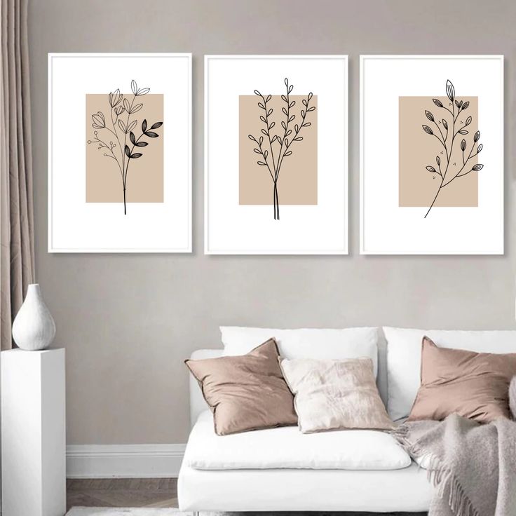 three framed art prints hanging on the wall above a white couch in a living room