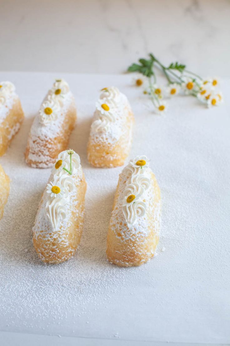 small pastries with flowers on top of a white surface next to some dried flowers