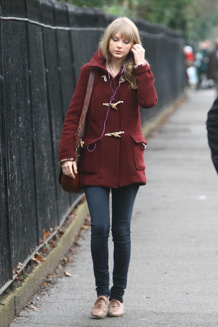 a woman is walking down the street talking on her cell phone while wearing a red coat