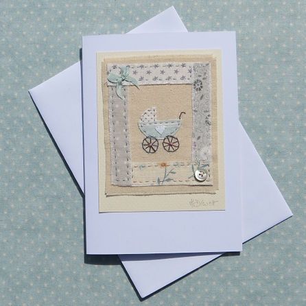 two cards with an embroidered baby carriage on them, one is white and the other is blue