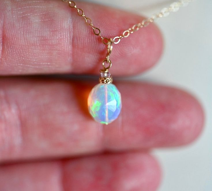 Choose from a selection of three unique opal charms crafted from 14K solid gold and opal, each adorned with an accent gemstone. The opals and gemstones used are all natural, complemented by the addition of 14K gold beads for a touch of elegance. Please note that the chain is not included with this pendant. Gold Opal Birthstone Ring As Gift, Iridescent Opal Round Jewelry, Iridescent Round Opal Jewelry, Iridescent Opal Jewelry, White Opal Birthstone Jewelry, Dainty Round Ethiopian Opal Jewelry, Dainty Pink Opal Gemstone Jewelry, Dainty Ethiopian Opal Round Jewelry, Handmade Pink Opal Round Jewelry