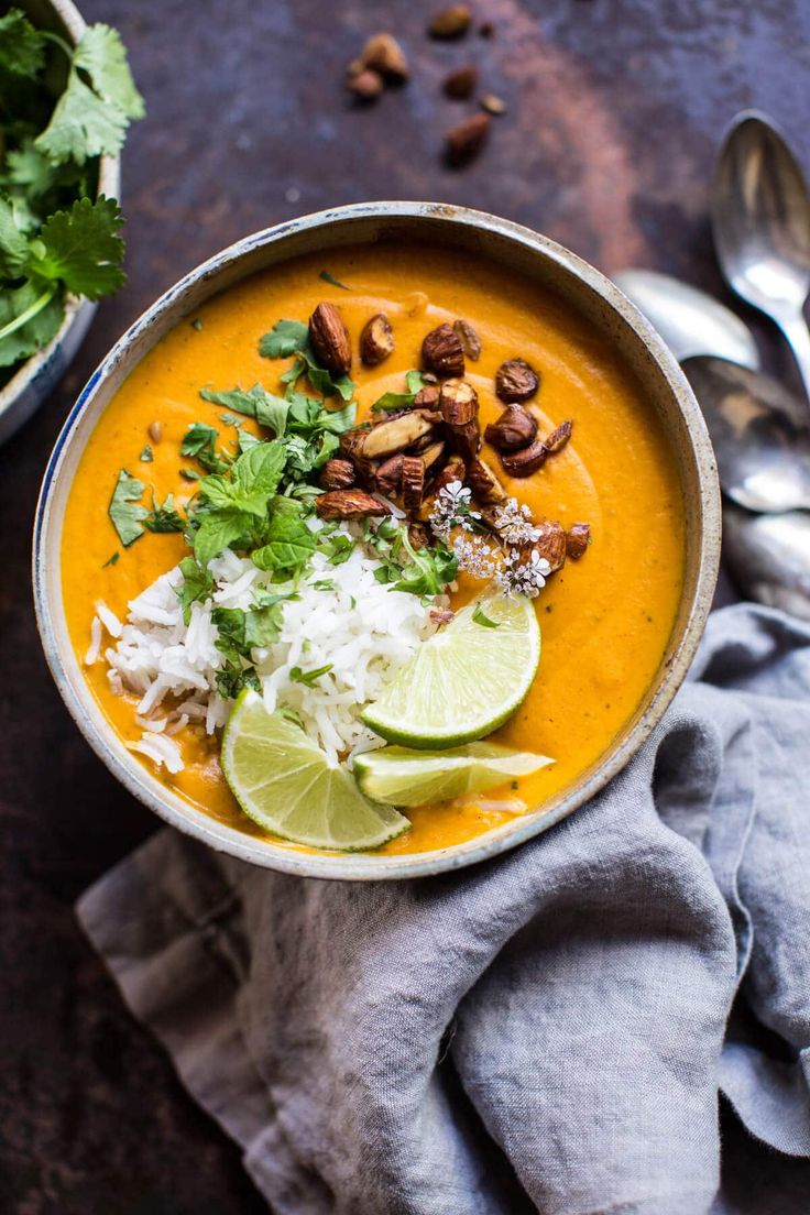 a bowl filled with soup and garnished with cilantro, limes, nuts