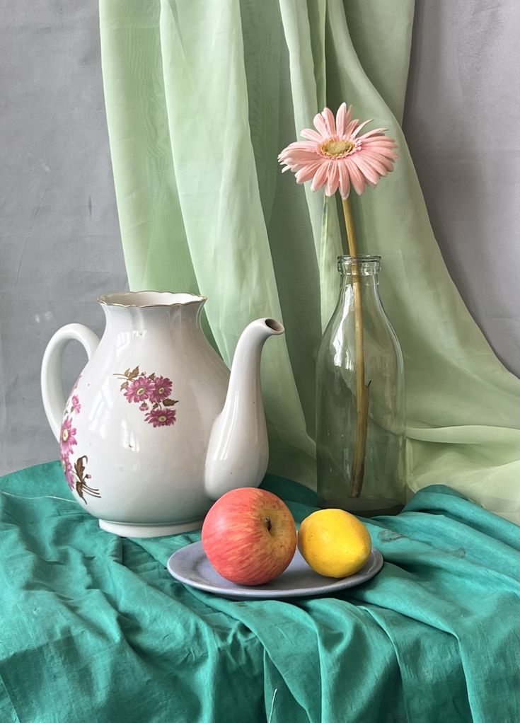 two apples and an apple on a plate next to a vase