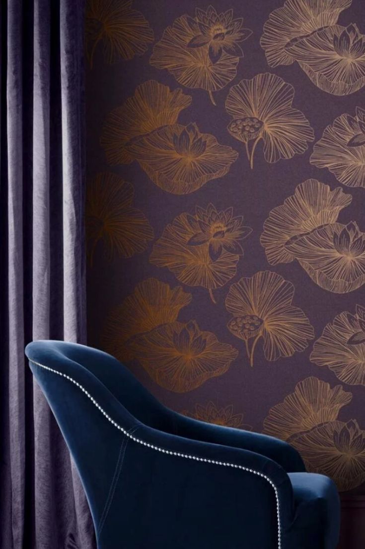 a blue chair sitting in front of a purple wall with gold leaf designs on it