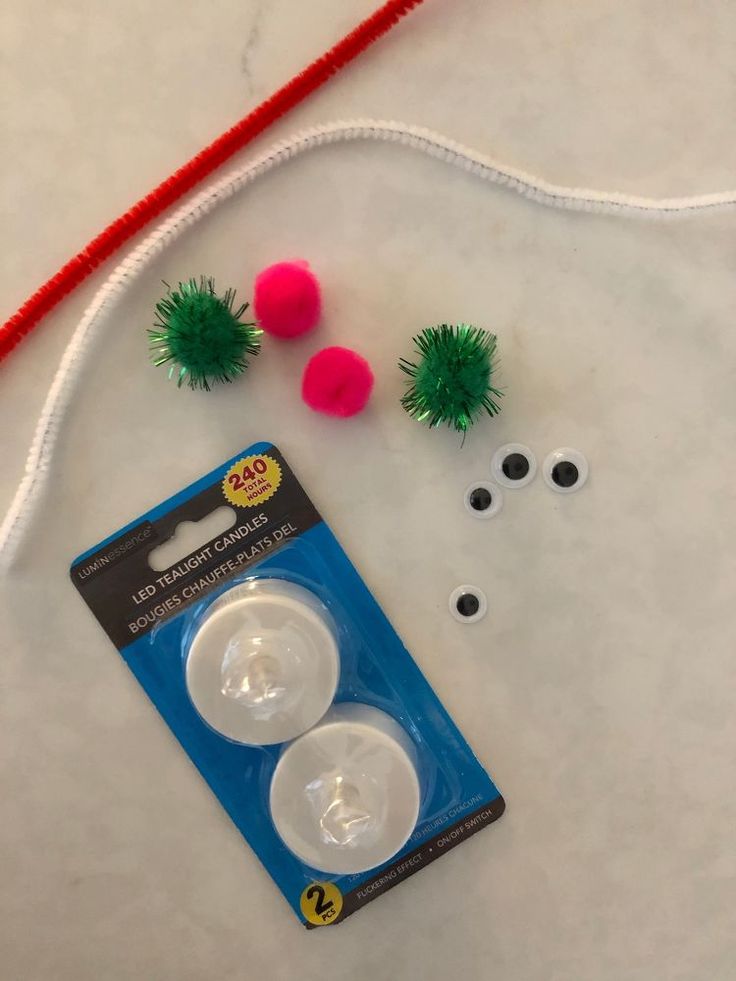 two pom poms are sitting on the table next to some yarn and beads