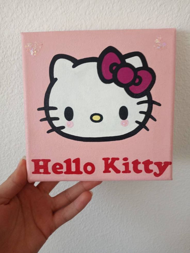 a hand holding up a pink hello kitty box with the word hello kitty on it