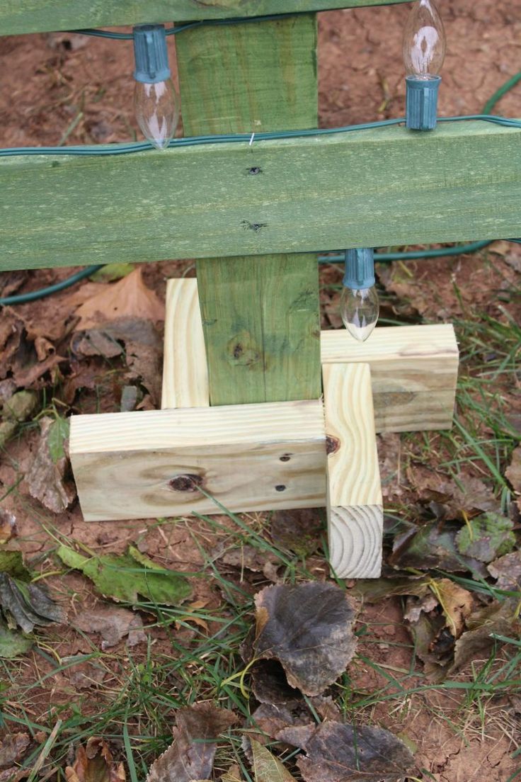 a wooden bench with two lights attached to it's back and some leaves on the ground