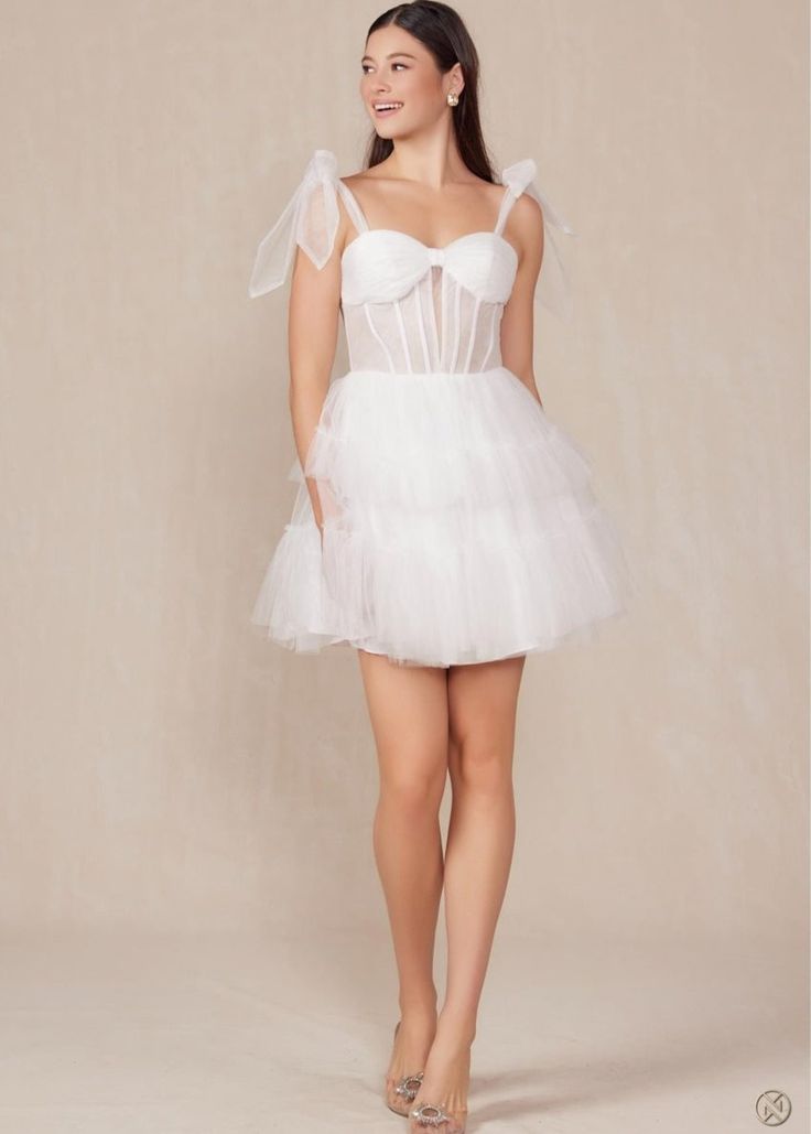 How dreamy is this White Tulle A-Line Mini?! Tulle Tie straps meet a ruched bandeau style bust and corset style bodice and flow into a layered tulle skirt. This dress will have you twirling on the dance floor all night long! Finished with an invisible zipper. Final Sale. Looking for a different size? Message us to inquire about availability to special order in sizes 00-16, don't forget to include the date of your event! Mini Tulle Dresses With Corset Back, Mini Tulle Dress With Corset Back, Fitted Tulle Strapless Dress With Corset Back, Fitted Strapless Tulle Dress With Corset Back, Fitted Strapless Dress With Corset Back, Strapless Sweetheart Neckline Dress With Ruffles For Debutante Ball, Strapless Fitted Dress With Sweetheart Neckline And Tulle Skirt, Fitted Bodice Tulle Tutu Dress For Prom, Strapless Ruffle Dress With Sweetheart Neckline For Debutante Ball