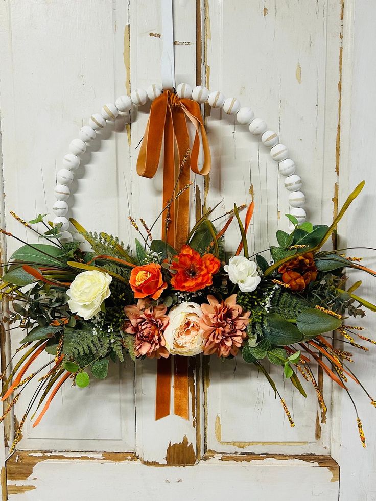 a wreath with flowers hanging on a door